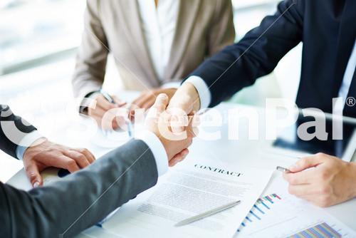 Image Of Business Partners Handshaking Over Business Objects On Workplace